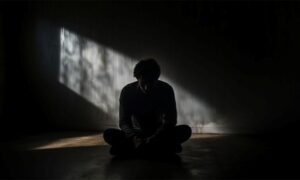 شخصی که در تاریکی و افسرده نشسته است
